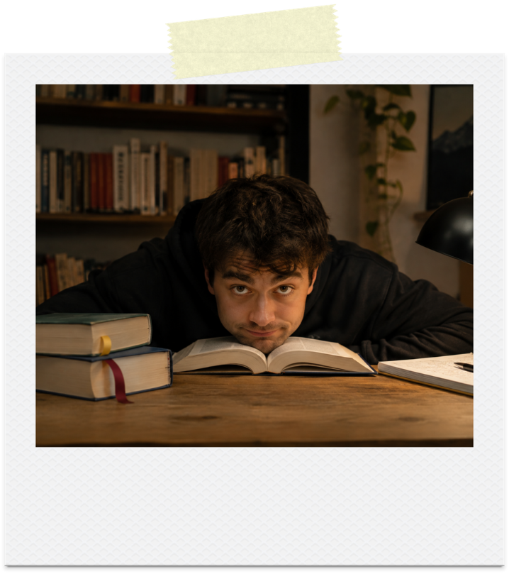 A man peeking over an open book, overwhelmed, at his desk