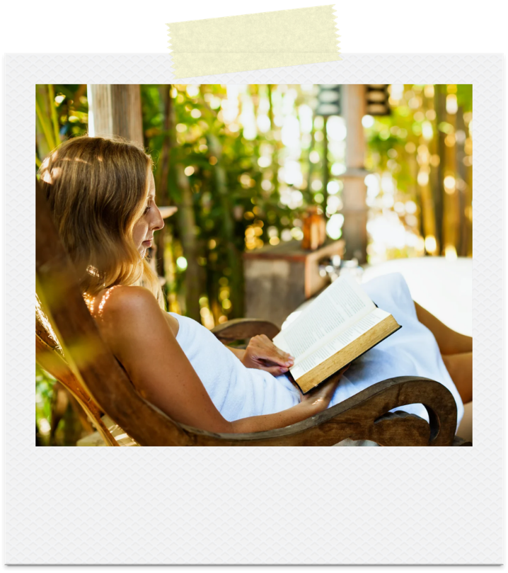 A woman reading on a porch surrounded by greenery